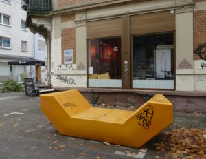 Eine orange Sitzfläche, genannt "Enzi" vor einer Fensterfront